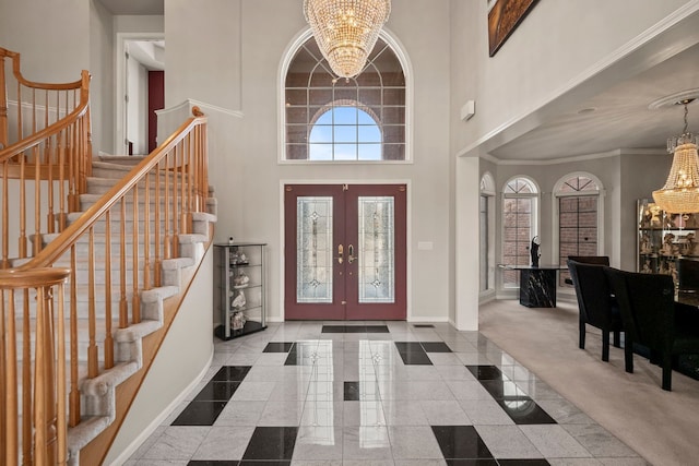 entryway featuring a notable chandelier, a towering ceiling, baseboards, and granite finish floor