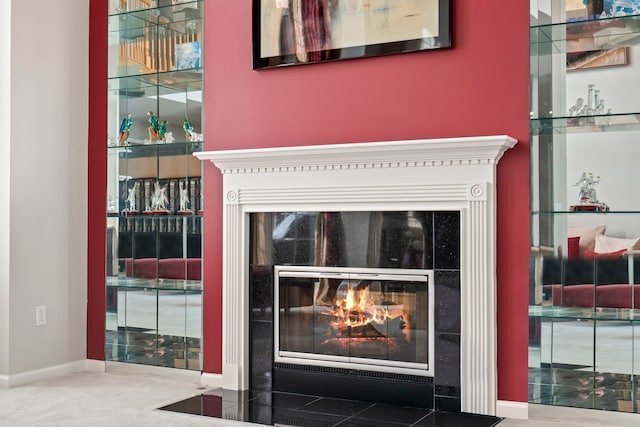 interior details with a tiled fireplace and baseboards