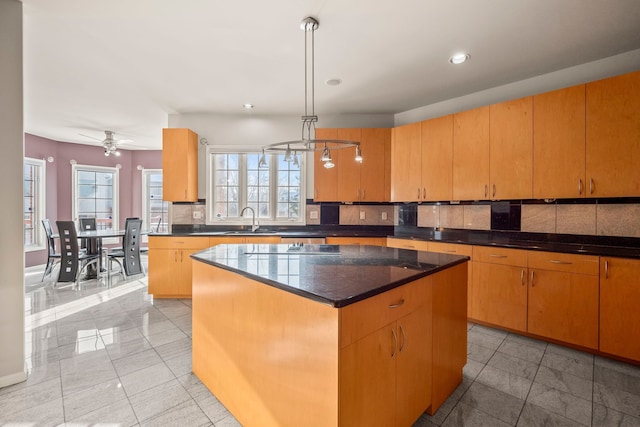 kitchen featuring a center island, pendant lighting, recessed lighting, backsplash, and a sink