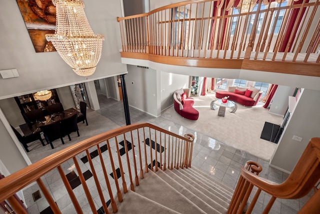 stairs featuring baseboards, a towering ceiling, and a notable chandelier