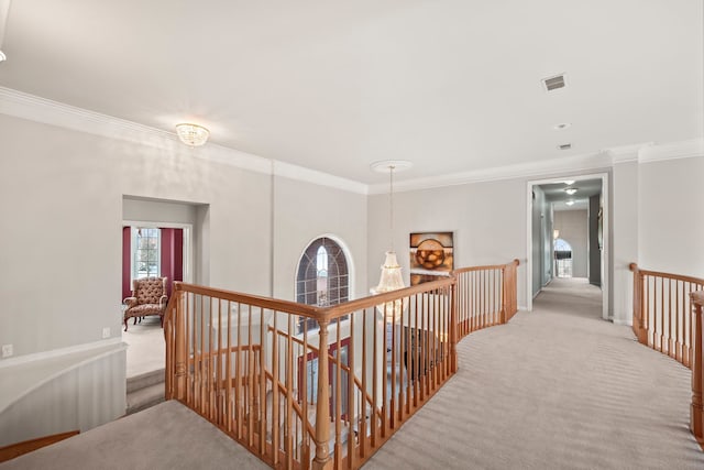 hall with light carpet, an upstairs landing, visible vents, and ornamental molding