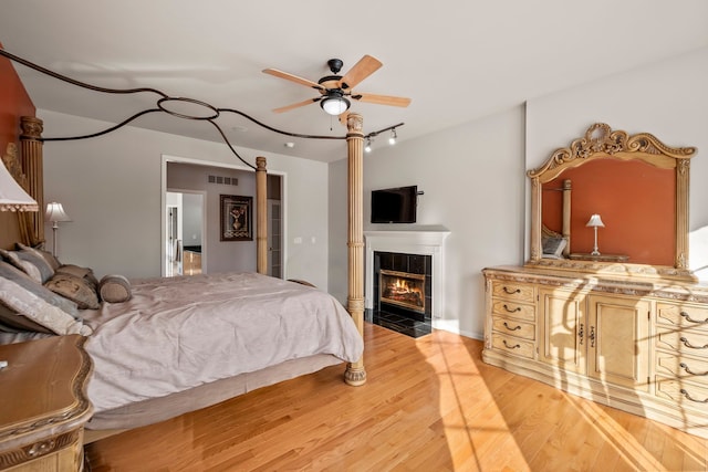 bedroom with light wood-type flooring, visible vents, and a fireplace