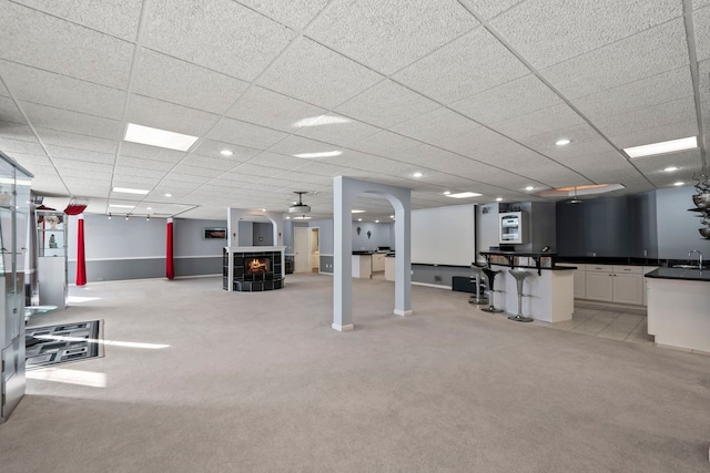 workout room featuring arched walkways, recessed lighting, light colored carpet, a tiled fireplace, and a sink