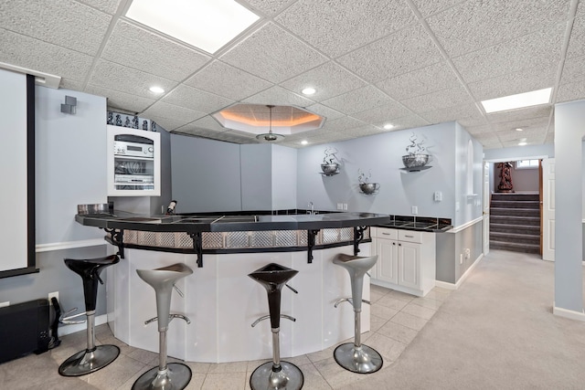 kitchen featuring a breakfast bar, dark countertops, a paneled ceiling, recessed lighting, and baseboards