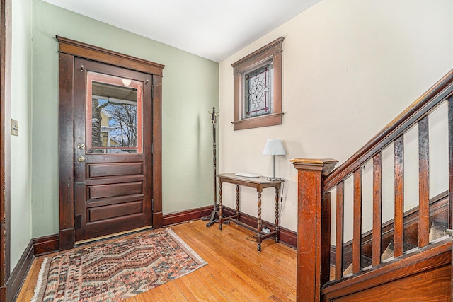 foyer with wood-type flooring, stairs, and baseboards