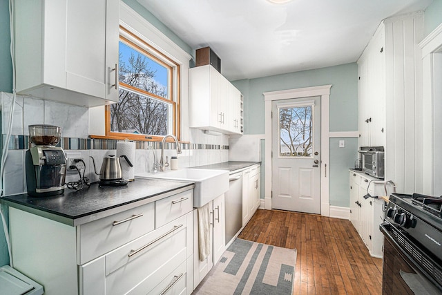 kitchen with dark wood-style floors, dark countertops, decorative backsplash, white cabinets, and black range with gas cooktop