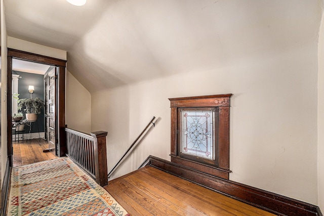 interior space featuring lofted ceiling, baseboards, and hardwood / wood-style floors