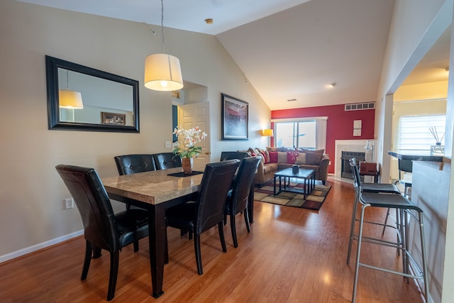 dining area with plenty of natural light, a tiled fireplace, visible vents, and wood finished floors