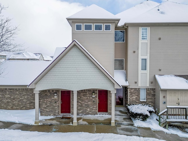 townhome / multi-family property with covered porch and brick siding