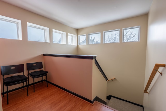 living area with light wood-type flooring, baseboards, and an upstairs landing