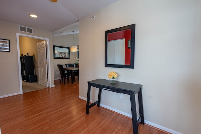 corridor with light wood-type flooring, baseboards, and visible vents