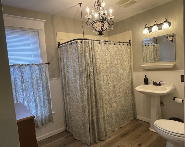 bathroom featuring toilet, wood finished floors, visible vents, and an inviting chandelier