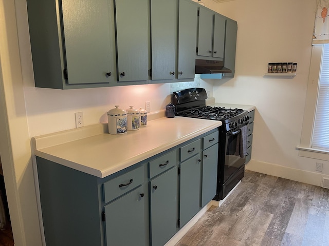 kitchen featuring under cabinet range hood, baseboards, light countertops, gas stove, and dark wood finished floors