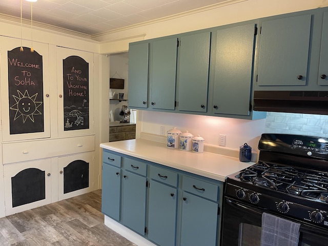 kitchen featuring under cabinet range hood, light wood-style floors, light countertops, ornamental molding, and gas stove