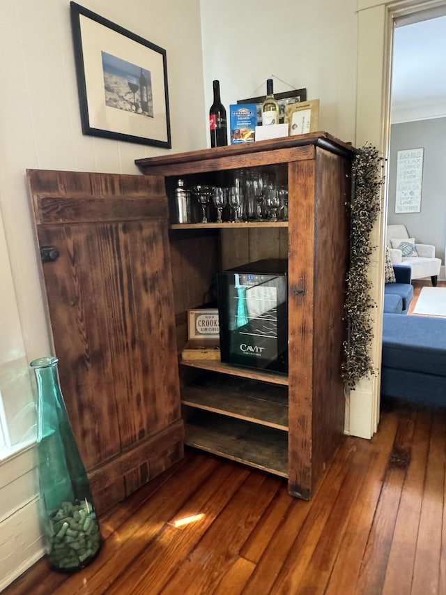 room details featuring ornamental molding, a dry bar, and wood finished floors