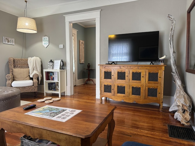 living room with ornamental molding, wood finished floors, visible vents, and baseboards