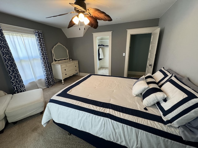 bedroom featuring ceiling fan, carpet floors, vaulted ceiling, and a walk in closet