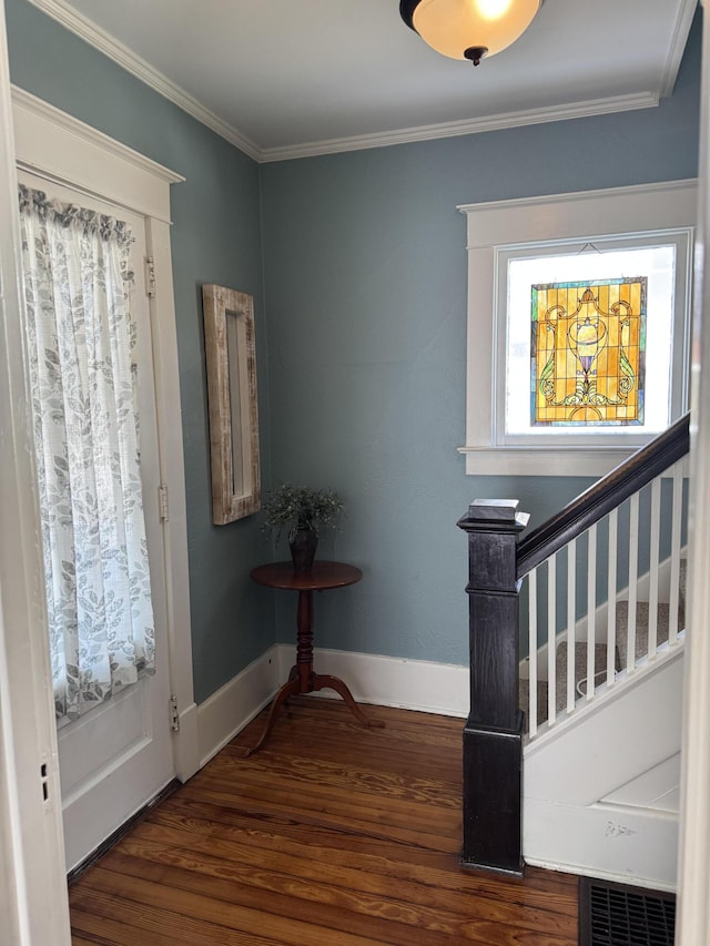 foyer entrance with stairs, crown molding, baseboards, and wood finished floors