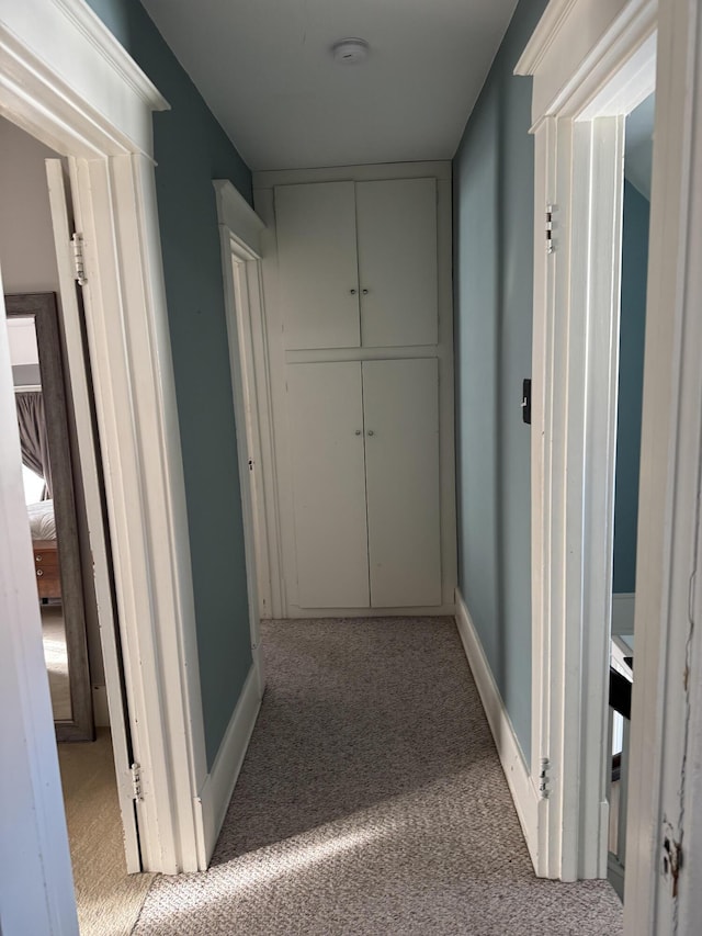 hall featuring baseboards and light colored carpet