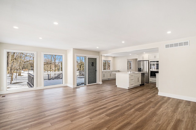 unfurnished living room with recessed lighting, visible vents, a sink, and wood finished floors