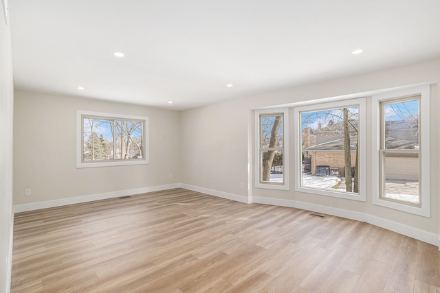 spare room with light wood finished floors, plenty of natural light, and baseboards