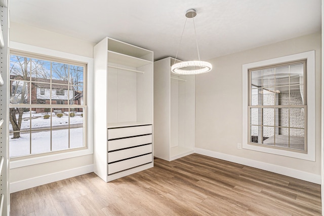 unfurnished dining area featuring a healthy amount of sunlight, baseboards, and wood finished floors