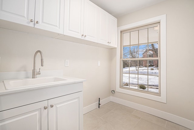 washroom with cabinet space, light tile patterned flooring, a sink, and baseboards