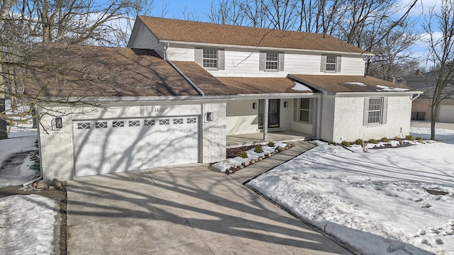 view of front of home with driveway, brick siding, an attached garage, and a shingled roof