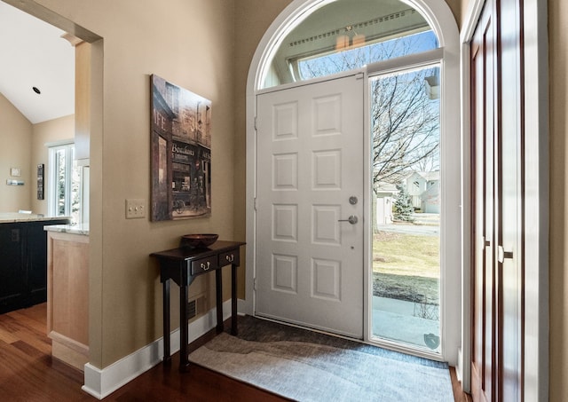 entryway featuring lofted ceiling, baseboards, and dark wood-style flooring