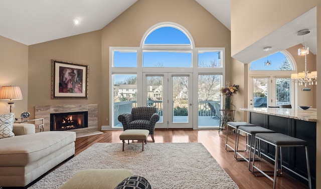 living area featuring a notable chandelier, wood finished floors, a high end fireplace, and high vaulted ceiling