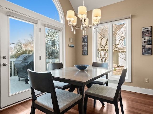 dining room with an inviting chandelier, wood finished floors, baseboards, and vaulted ceiling