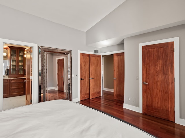 unfurnished bedroom featuring vaulted ceiling, wood finished floors, visible vents, and baseboards