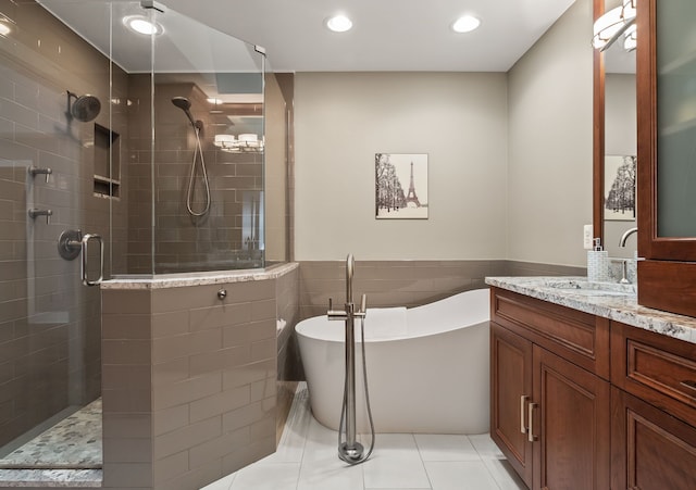 full bath featuring vanity, tiled shower, a soaking tub, wainscoting, and tile walls