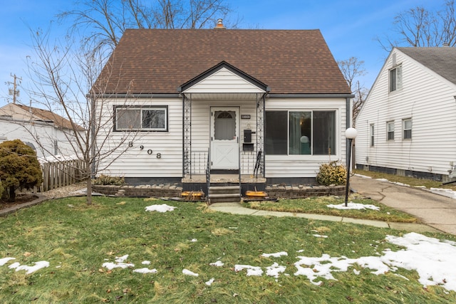 view of front of home with a front lawn, roof with shingles, and a chimney