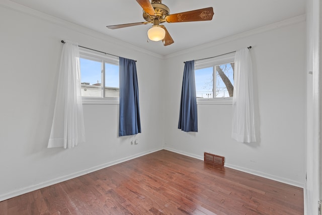 unfurnished room featuring visible vents, ornamental molding, a ceiling fan, wood finished floors, and baseboards