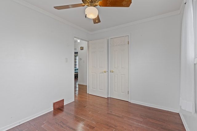 unfurnished room with baseboards, visible vents, ceiling fan, ornamental molding, and wood finished floors