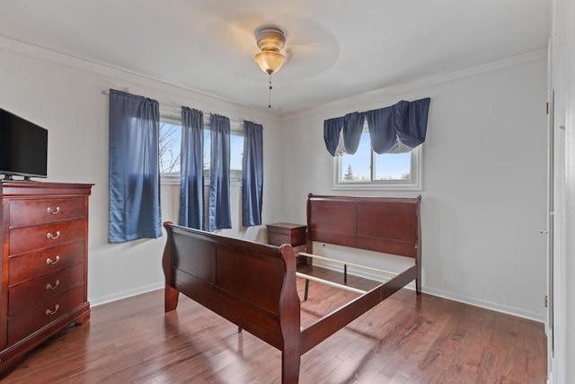 bedroom with ornamental molding, multiple windows, wood finished floors, and baseboards