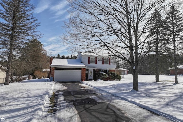 view of front of house with an attached garage, aphalt driveway, and brick siding