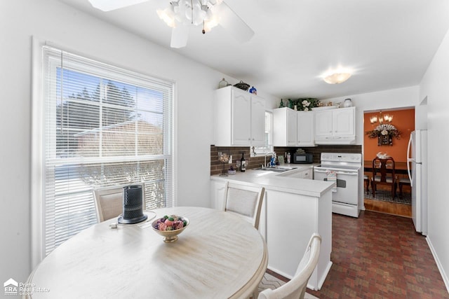 kitchen with white appliances, white cabinets, a peninsula, light countertops, and a sink