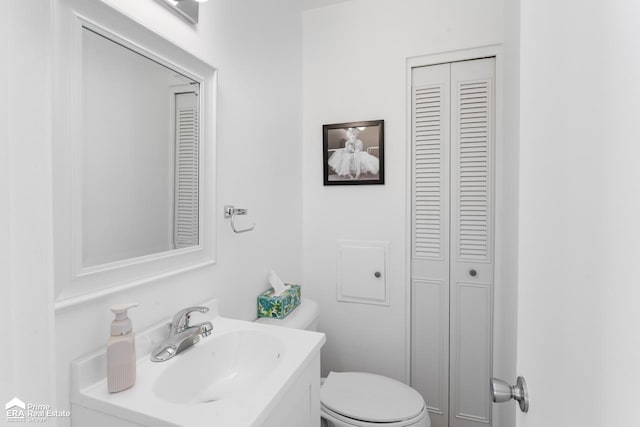 bathroom with a closet, vanity, and toilet