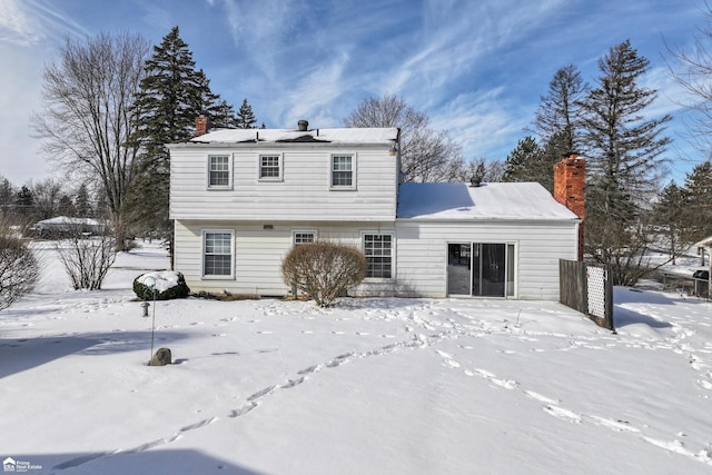 snow covered rear of property featuring a chimney