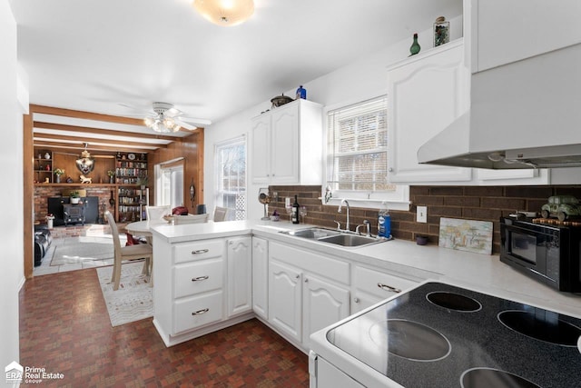 kitchen with white cabinets, electric stove, a peninsula, light countertops, and a sink