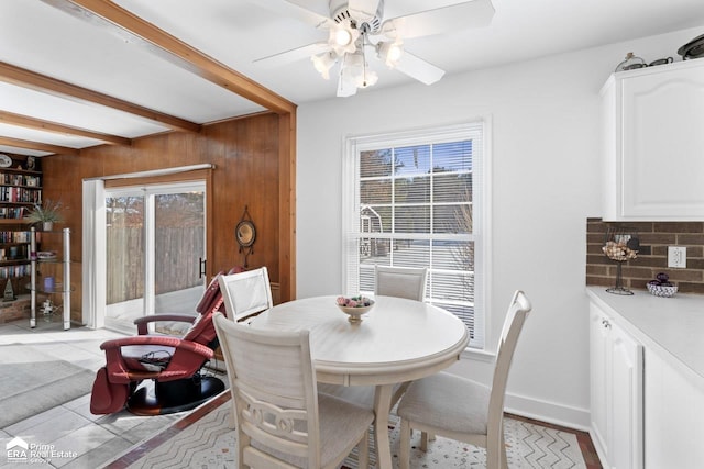 dining room with plenty of natural light, baseboards, ceiling fan, and beamed ceiling