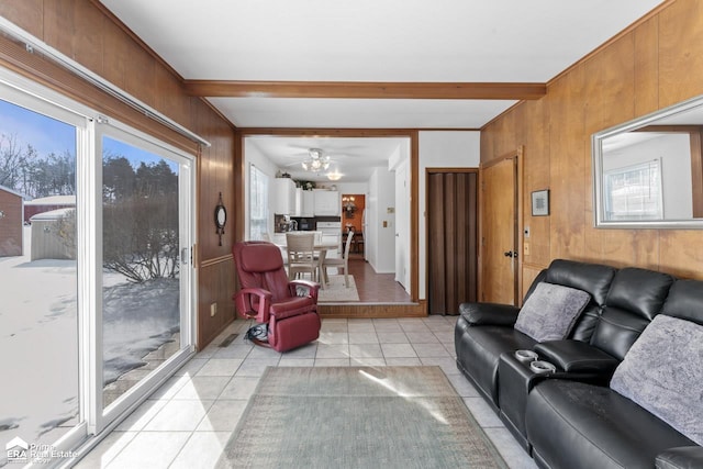 living room with wooden walls, a ceiling fan, beam ceiling, and light tile patterned flooring