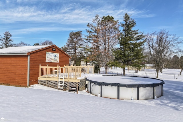 snowy yard featuring a deck and a covered pool