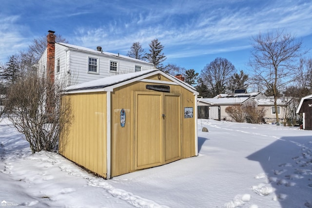 snow covered structure with an outbuilding and a shed