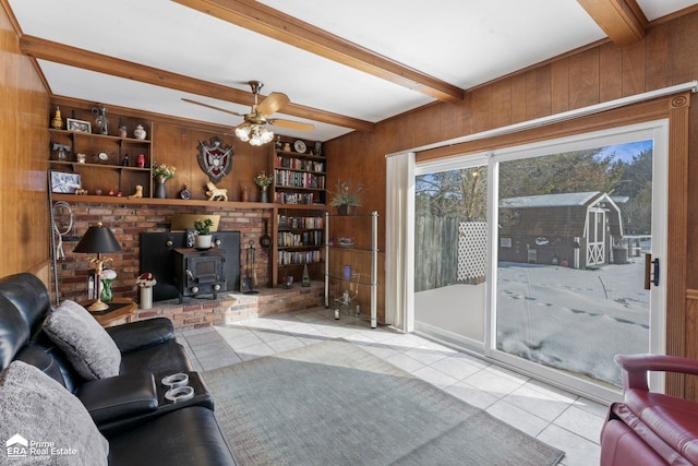 living area with a wood stove, light tile patterned floors, and wooden walls