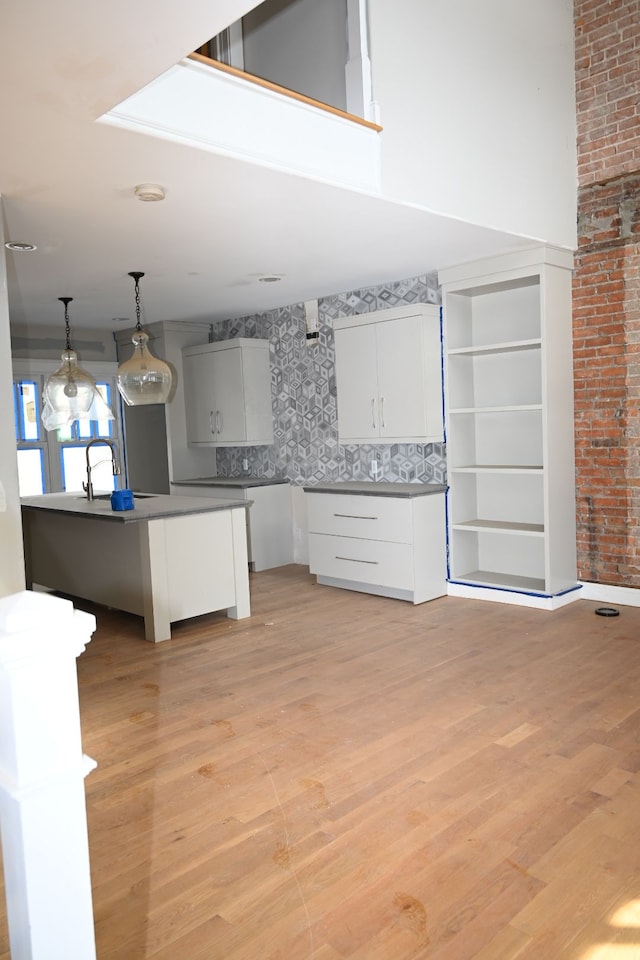 kitchen with light wood-style floors, dark countertops, white cabinetry, and hanging light fixtures