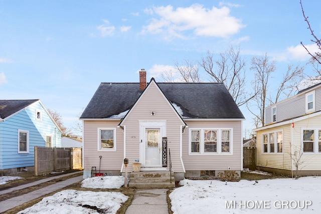 bungalow-style house featuring entry steps, roof with shingles, fence, and a chimney