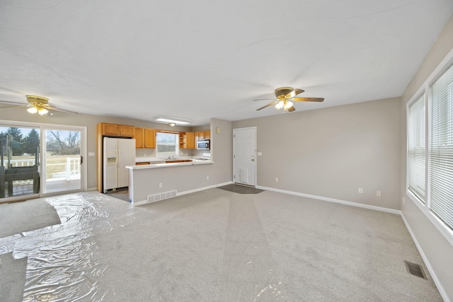 unfurnished living room with light colored carpet, visible vents, and baseboards